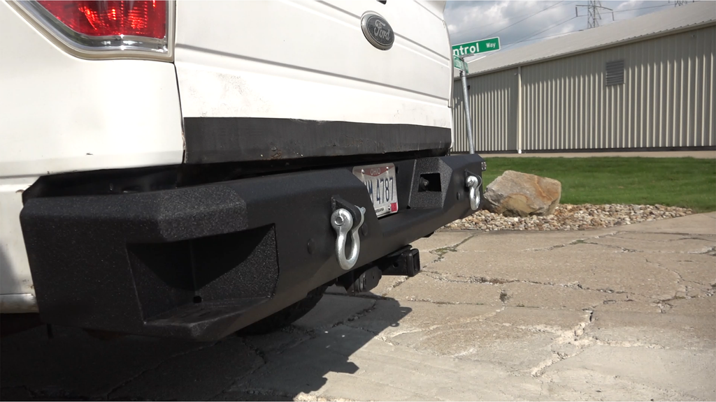 Durable and stylish Fishbone Offroad Rear Recovery Step Bumper for 2009-2014 Ford F-150, showcasing integrated steps and a built-in bottle opener.