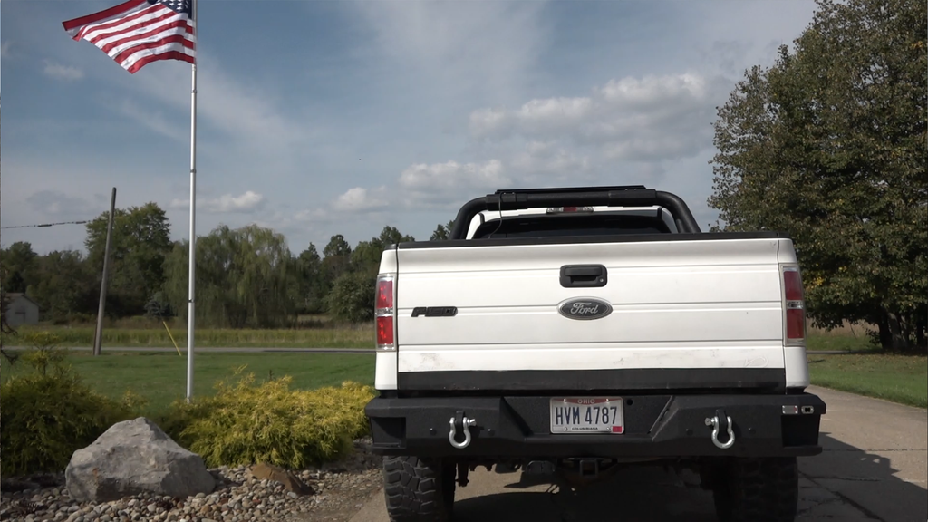 Durable and stylish Fishbone Offroad Rear Recovery Step Bumper for 2009-2014 Ford F-150, showcasing integrated steps and a built-in bottle opener.