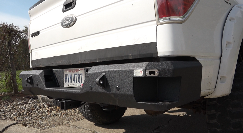 Durable and stylish Fishbone Offroad Rear Recovery Step Bumper for 2009-2014 Ford F-150, showcasing integrated steps and a built-in bottle opener.