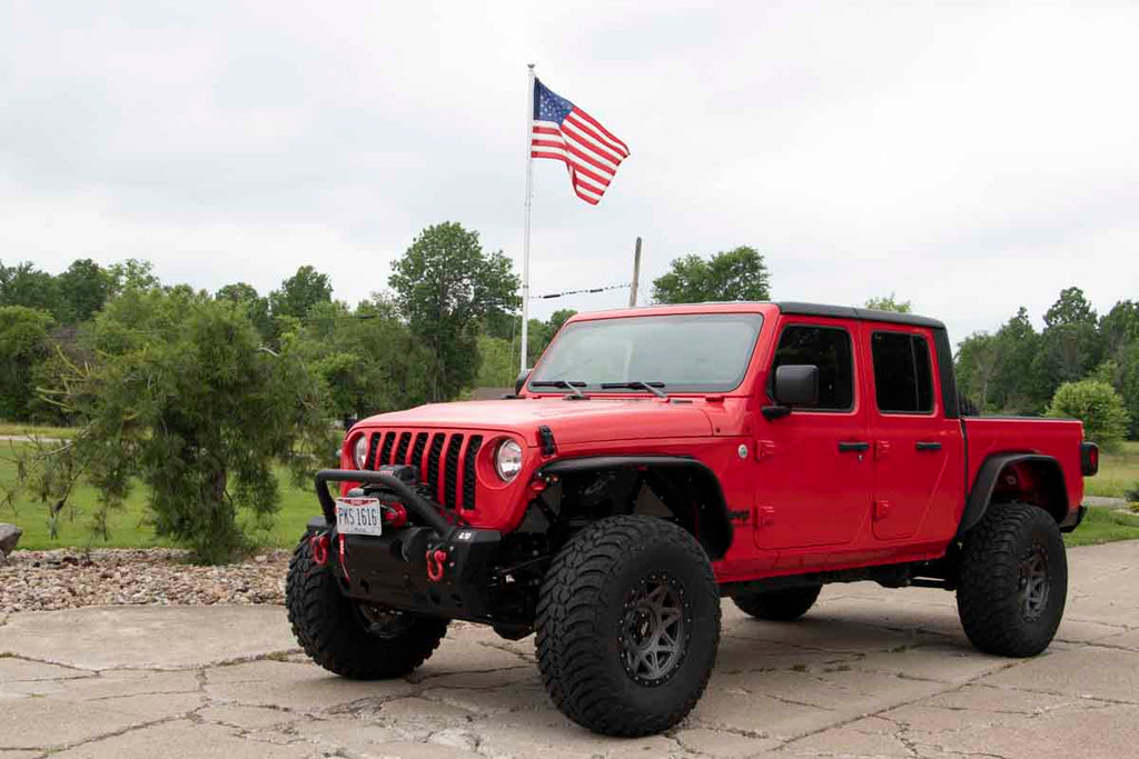 Fishbone Offroad Front Stubby Winch Bumper, perfectly contoured under a Jeep grill, showcasing durability and rugged elegance.