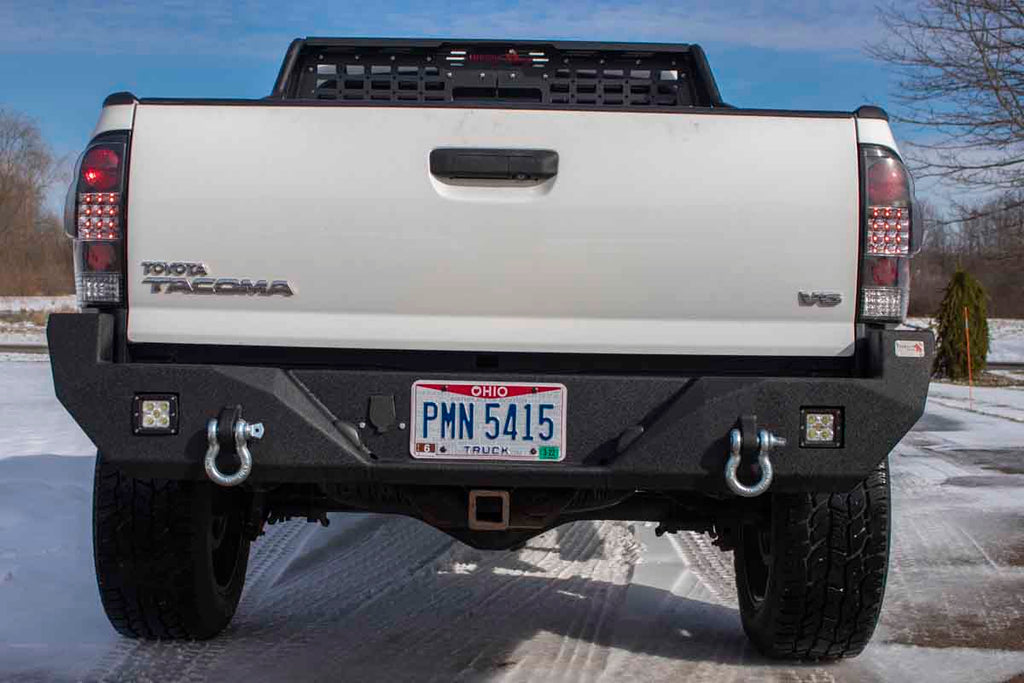 Durable Fishbone Offroad rear bumper, designed precisely for the 2005-2015 Toyota Tacoma, showcasing provisions for LED cube lights and integrated D-ring mounts.