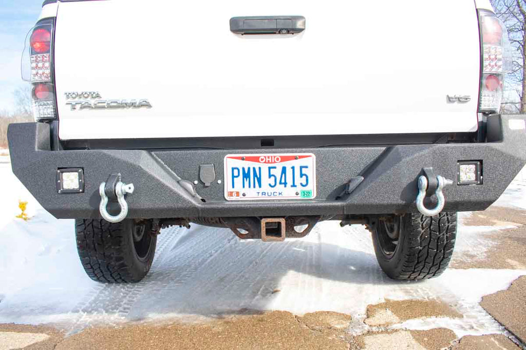 Durable Fishbone Offroad rear bumper, designed precisely for the 2005-2015 Toyota Tacoma, showcasing provisions for LED cube lights and integrated D-ring mounts.